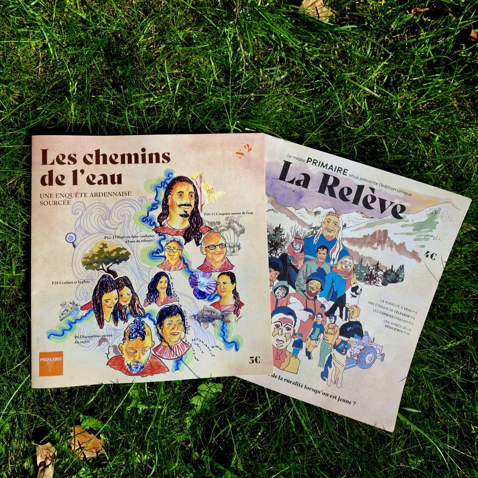 Pack de deux publications Primaire Média : le Journal N°2 et l'édition La Relève, posés côte à côte sur de l'herbe verte ensoleillée.
